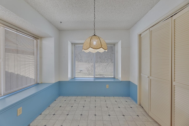 unfurnished dining area with a textured ceiling