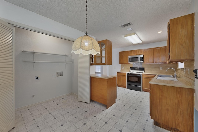 kitchen with sink, decorative backsplash, hanging light fixtures, stove, and a textured ceiling