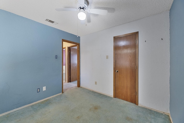 unfurnished bedroom with ceiling fan, light colored carpet, and a textured ceiling