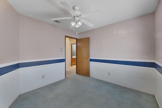 spare room with ceiling fan, light carpet, and a textured ceiling