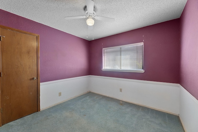 empty room with ceiling fan, a textured ceiling, and carpet