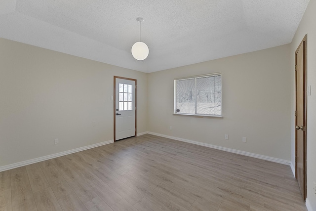 spare room featuring a textured ceiling and light hardwood / wood-style flooring