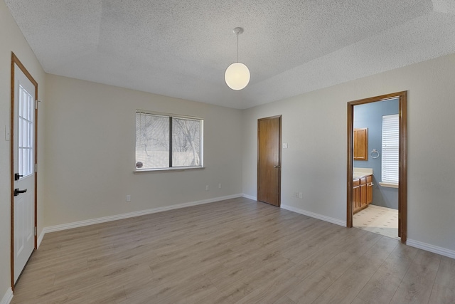 spare room featuring a textured ceiling and light hardwood / wood-style floors