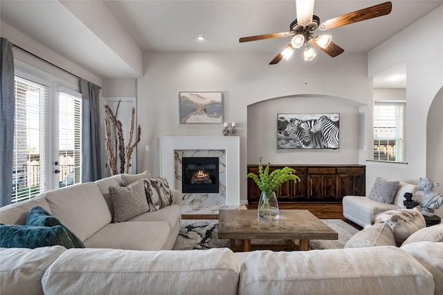 living room featuring wood-type flooring, a premium fireplace, and ceiling fan