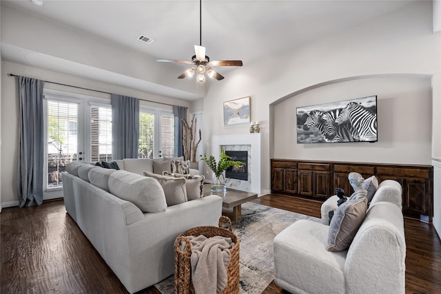 living room featuring dark hardwood / wood-style flooring, a high end fireplace, ceiling fan, and vaulted ceiling