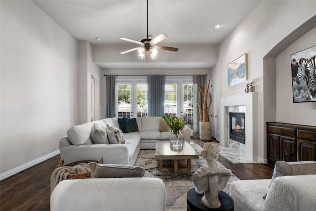 living room featuring ceiling fan, a high end fireplace, and dark hardwood / wood-style flooring