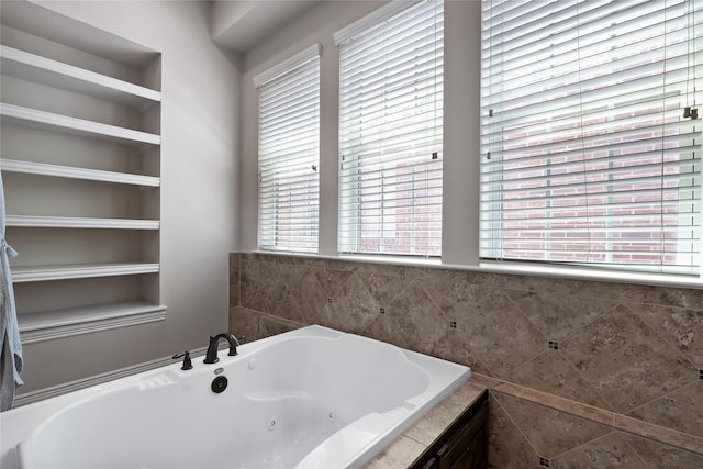 bathroom with a relaxing tiled tub and built in shelves