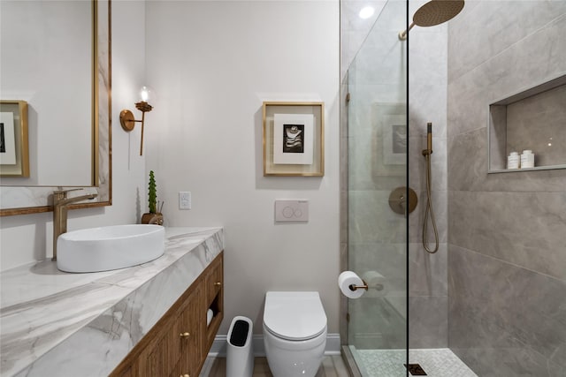 bathroom featuring vanity, a tile shower, and toilet