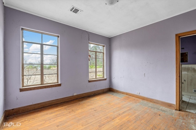 spare room featuring ornamental molding and light hardwood / wood-style flooring