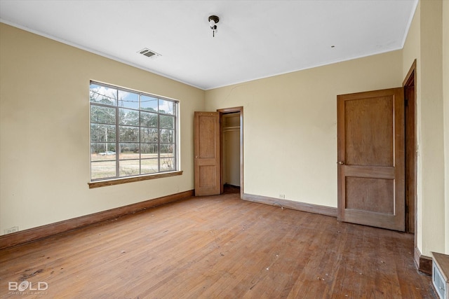 unfurnished bedroom featuring crown molding, light wood-type flooring, and a closet