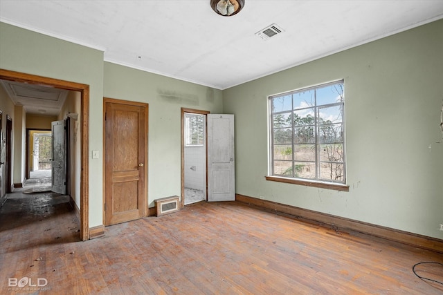 unfurnished bedroom featuring hardwood / wood-style flooring, crown molding, and multiple windows