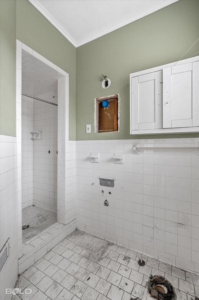 bathroom with tile walls, crown molding, and tiled shower