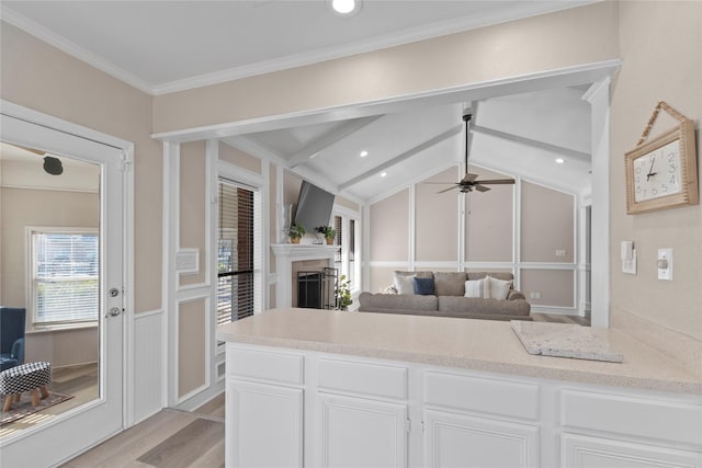 kitchen featuring ceiling fan, white cabinetry, vaulted ceiling with beams, ornamental molding, and light hardwood / wood-style floors