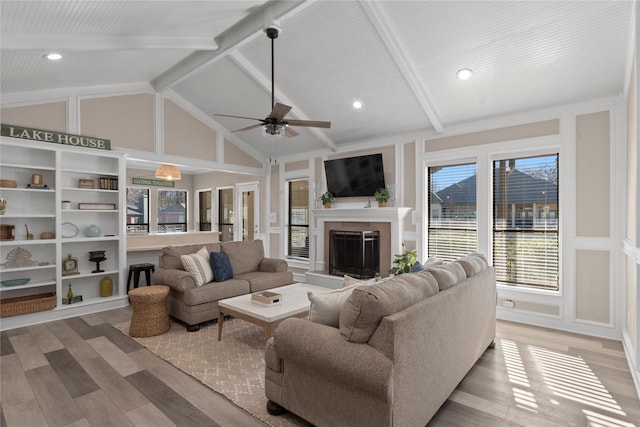 living room with high vaulted ceiling, light hardwood / wood-style floors, and beamed ceiling