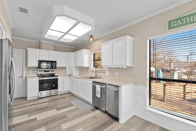 kitchen with white cabinetry, sink, light hardwood / wood-style floors, stainless steel appliances, and crown molding