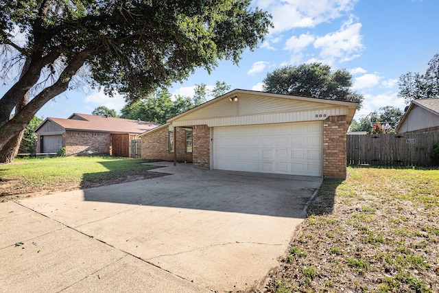 ranch-style home with a garage, an outdoor structure, and a front yard