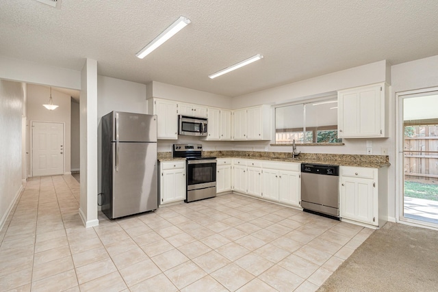 kitchen featuring pendant lighting, sink, white cabinetry, stainless steel appliances, and light tile patterned flooring