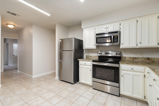 kitchen with light stone counters, stainless steel appliances, light tile patterned flooring, and white cabinets