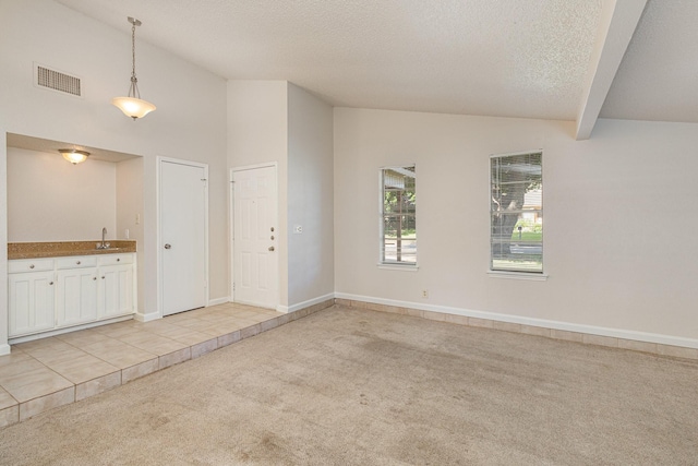 unfurnished room featuring lofted ceiling, sink, light carpet, and a textured ceiling