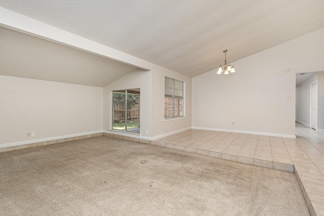 carpeted spare room featuring lofted ceiling, a textured ceiling, and a notable chandelier