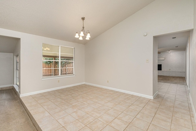 tiled spare room with an inviting chandelier, a fireplace, vaulted ceiling, and a textured ceiling