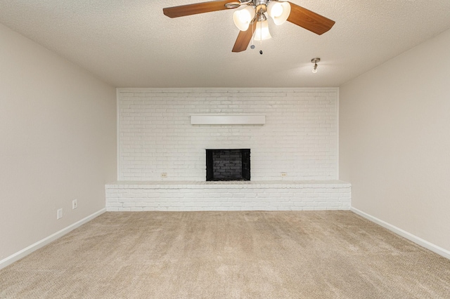 unfurnished living room featuring a brick fireplace, a textured ceiling, ceiling fan, brick wall, and carpet