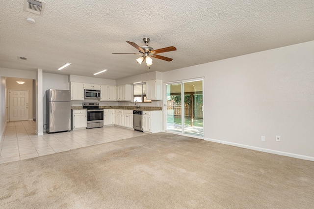 kitchen featuring white cabinetry, light colored carpet, ceiling fan, stainless steel appliances, and a textured ceiling