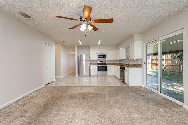 kitchen with light colored carpet, a textured ceiling, appliances with stainless steel finishes, ceiling fan, and white cabinets