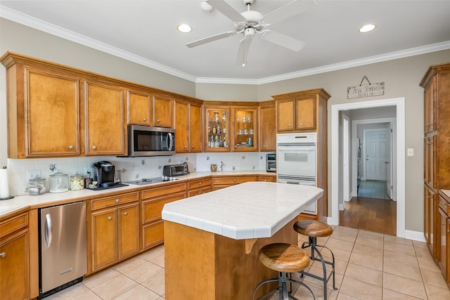 kitchen featuring white double oven, a kitchen island, fridge, a kitchen breakfast bar, and light tile patterned flooring