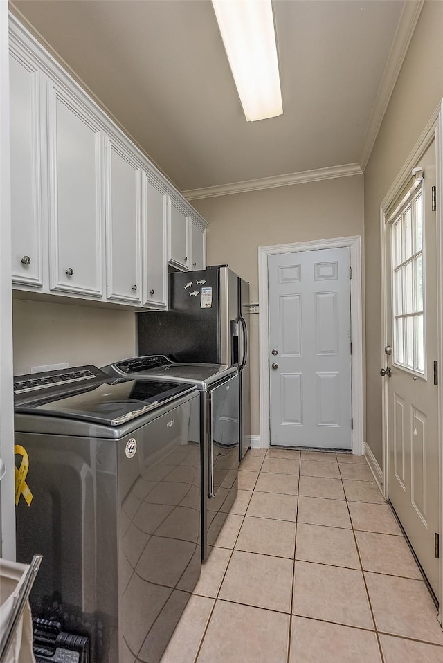 laundry room featuring cabinets, washing machine and dryer, light tile patterned floors, and crown molding