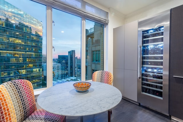 dining space featuring ornamental molding, dark wood-type flooring, and beverage cooler