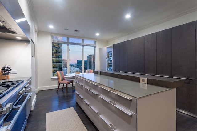 kitchen with stainless steel stove, dark hardwood / wood-style floors, ornamental molding, and a center island