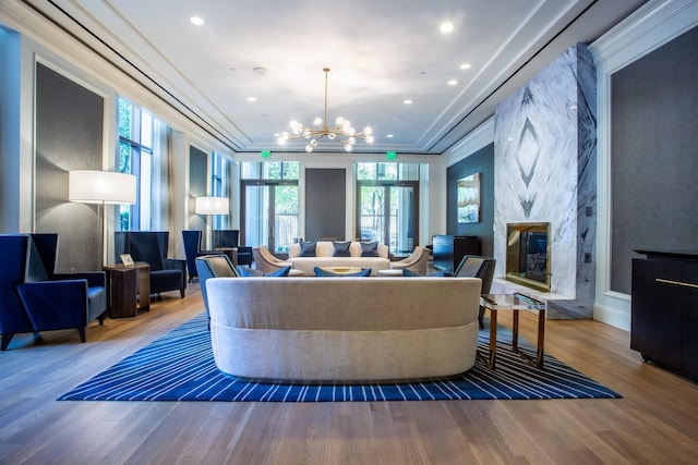 living room featuring an inviting chandelier, a high end fireplace, ornamental molding, and wood-type flooring