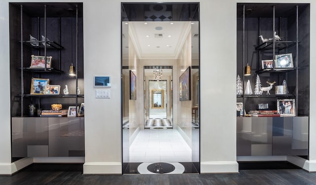 corridor with hardwood / wood-style flooring, ornamental molding, and an inviting chandelier