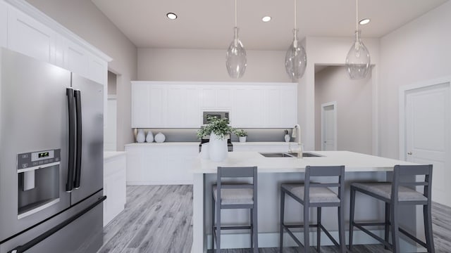 kitchen with pendant lighting, sink, white cabinetry, stainless steel refrigerator with ice dispenser, and an island with sink