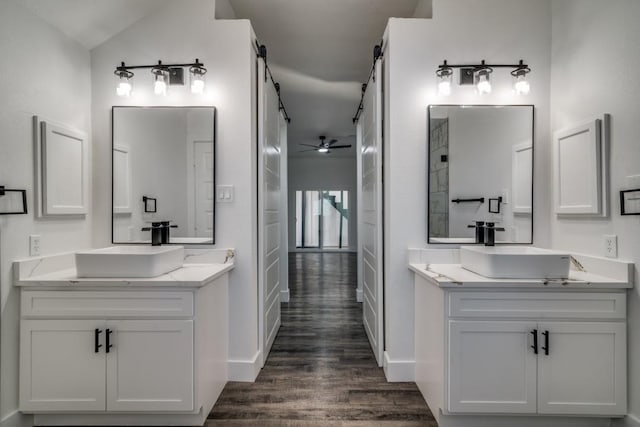 bathroom with a ceiling fan, two vanities, a sink, and wood finished floors