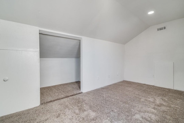 unfurnished bedroom with lofted ceiling, visible vents, and carpet flooring