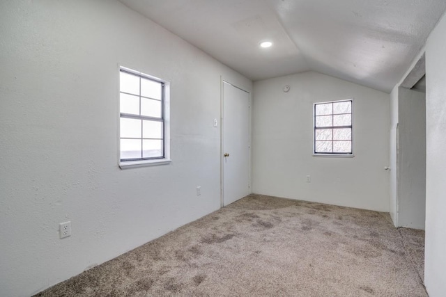 spare room with light carpet and vaulted ceiling