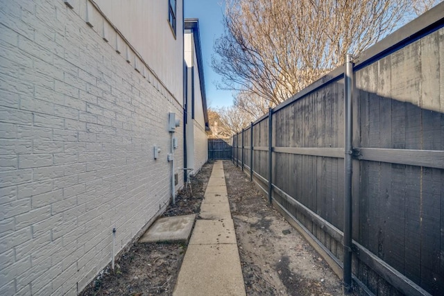 view of side of home featuring brick siding and fence