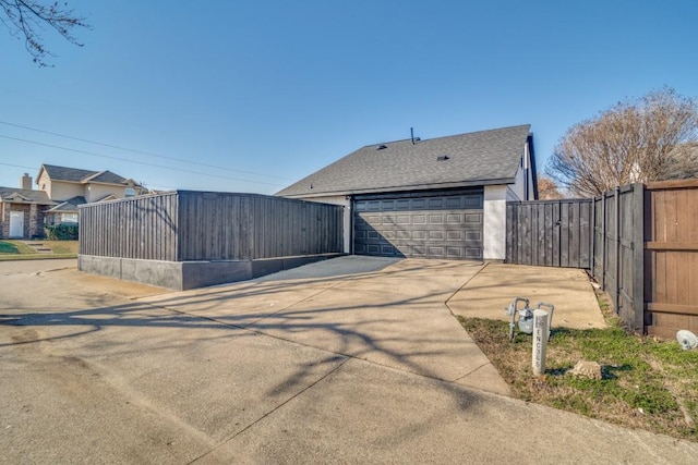 view of property exterior featuring a shingled roof, fence, and a garage