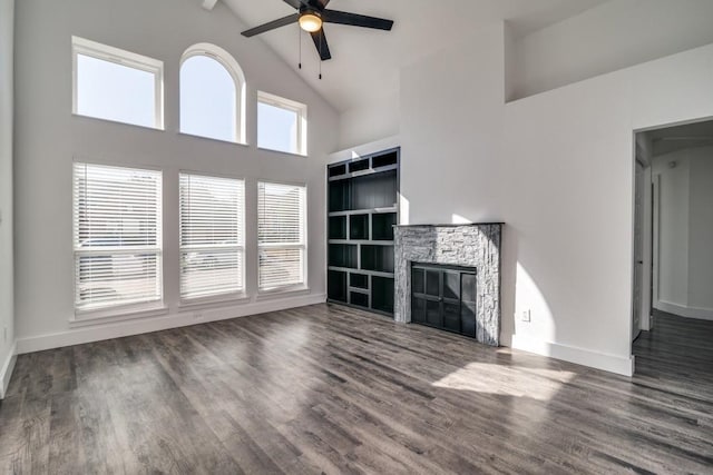 unfurnished living room featuring baseboards, ceiling fan, dark wood-type flooring, a stone fireplace, and high vaulted ceiling