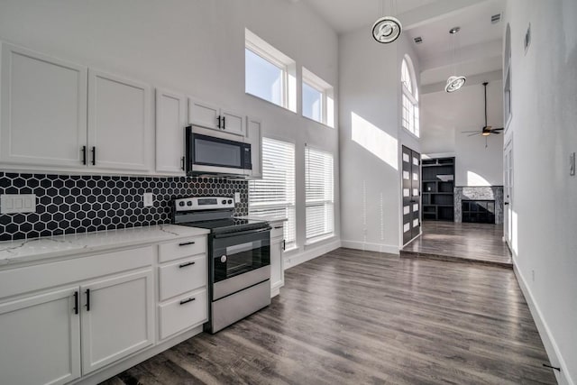 kitchen with light stone counters, stainless steel appliances, dark wood-style flooring, a fireplace, and white cabinetry