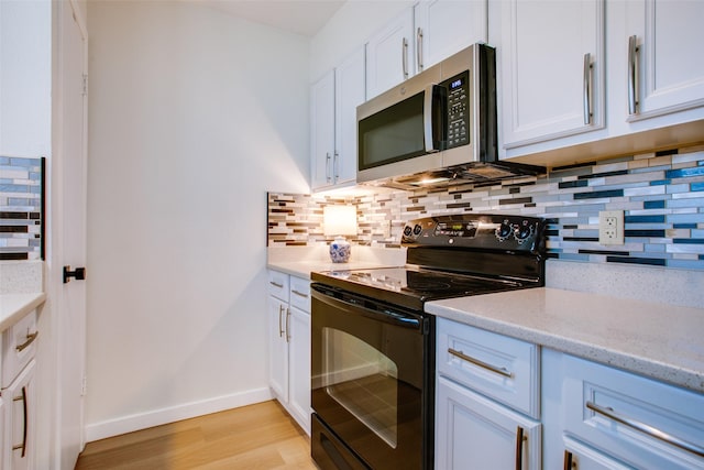 kitchen featuring light hardwood / wood-style flooring, light stone countertops, white cabinets, black / electric stove, and decorative backsplash