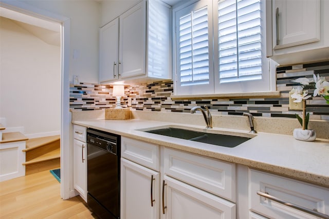 kitchen featuring sink, dishwasher, white cabinets, decorative backsplash, and light wood-type flooring