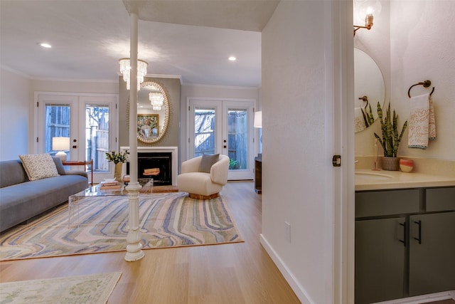 living room featuring sink, crown molding, light hardwood / wood-style flooring, and french doors