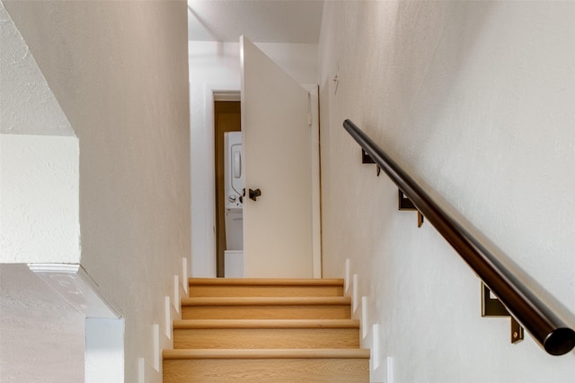 stairway featuring stacked washer and clothes dryer