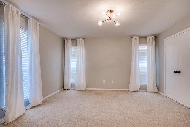 spare room with an inviting chandelier and light carpet