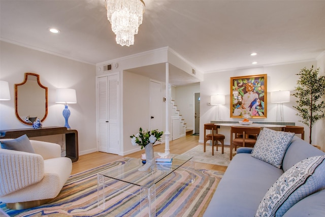 living room featuring crown molding, a chandelier, and light hardwood / wood-style flooring