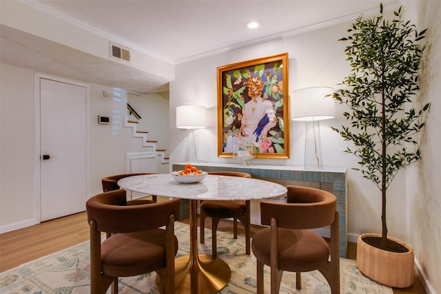 dining area featuring wood-type flooring and ornamental molding