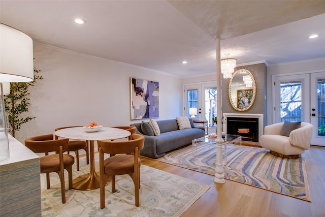 living room with french doors, crown molding, light hardwood / wood-style flooring, and a notable chandelier